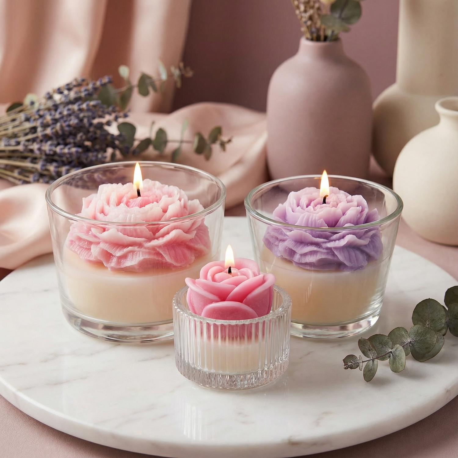 Handmade peony and rose cup candles with pink and purple flower designs in glass cups.