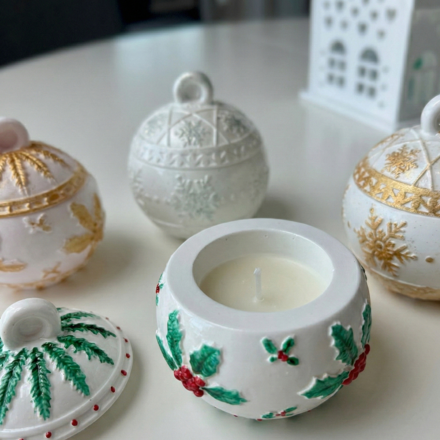 Decorative ceramic containers with a central candle on a white surface