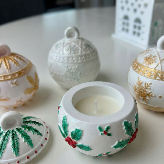 Decorative ceramic containers with a central candle on a white surface