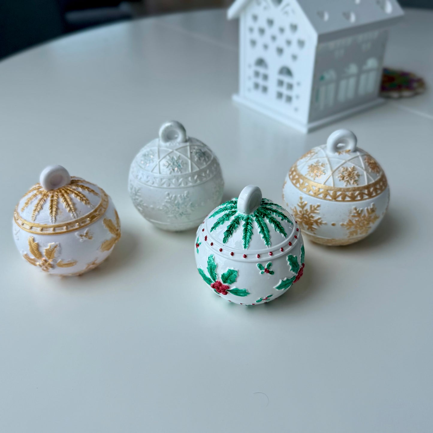Four decorative ceramic pots with different designs on a white surface.