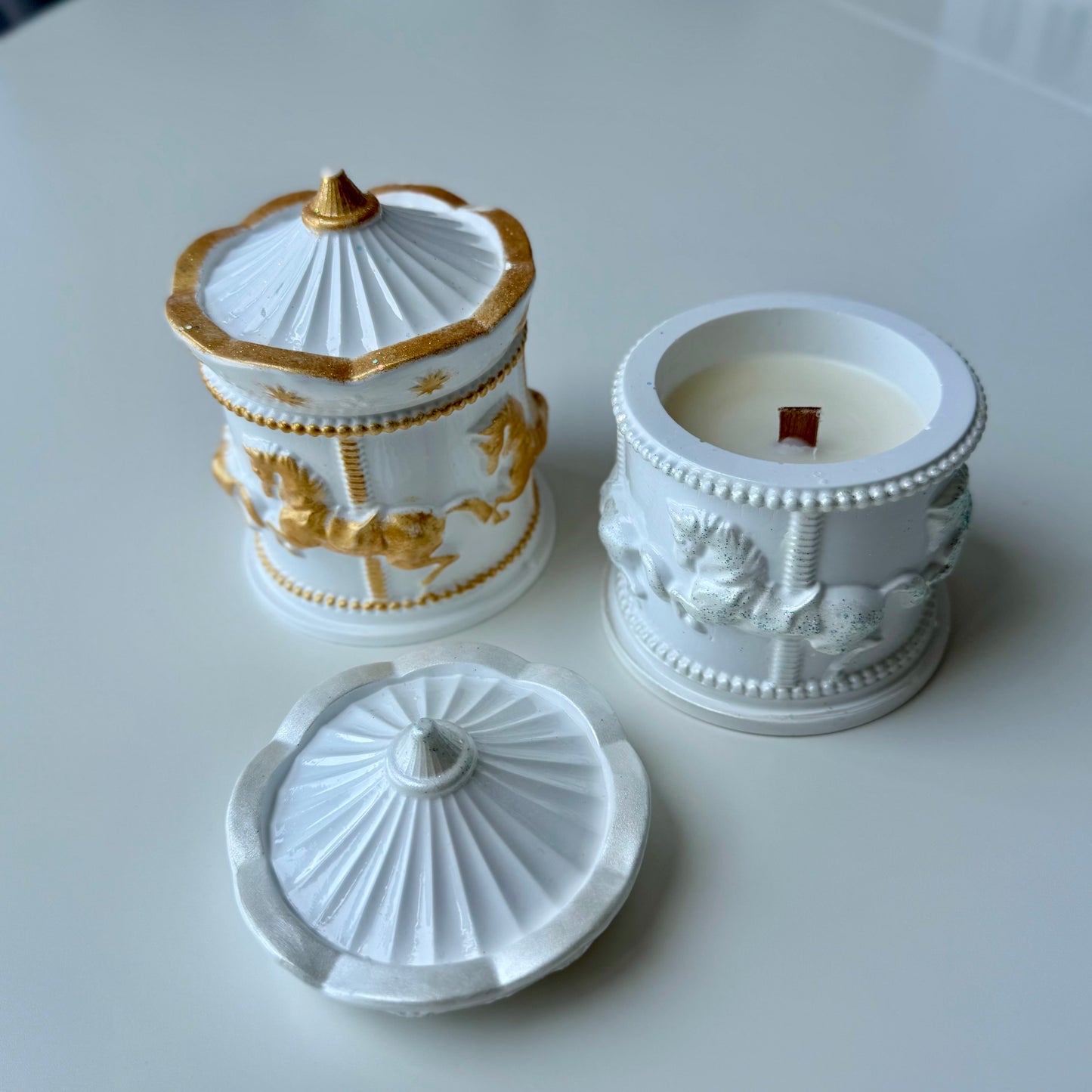 Decorative white and gold container with a candle on a light gray background