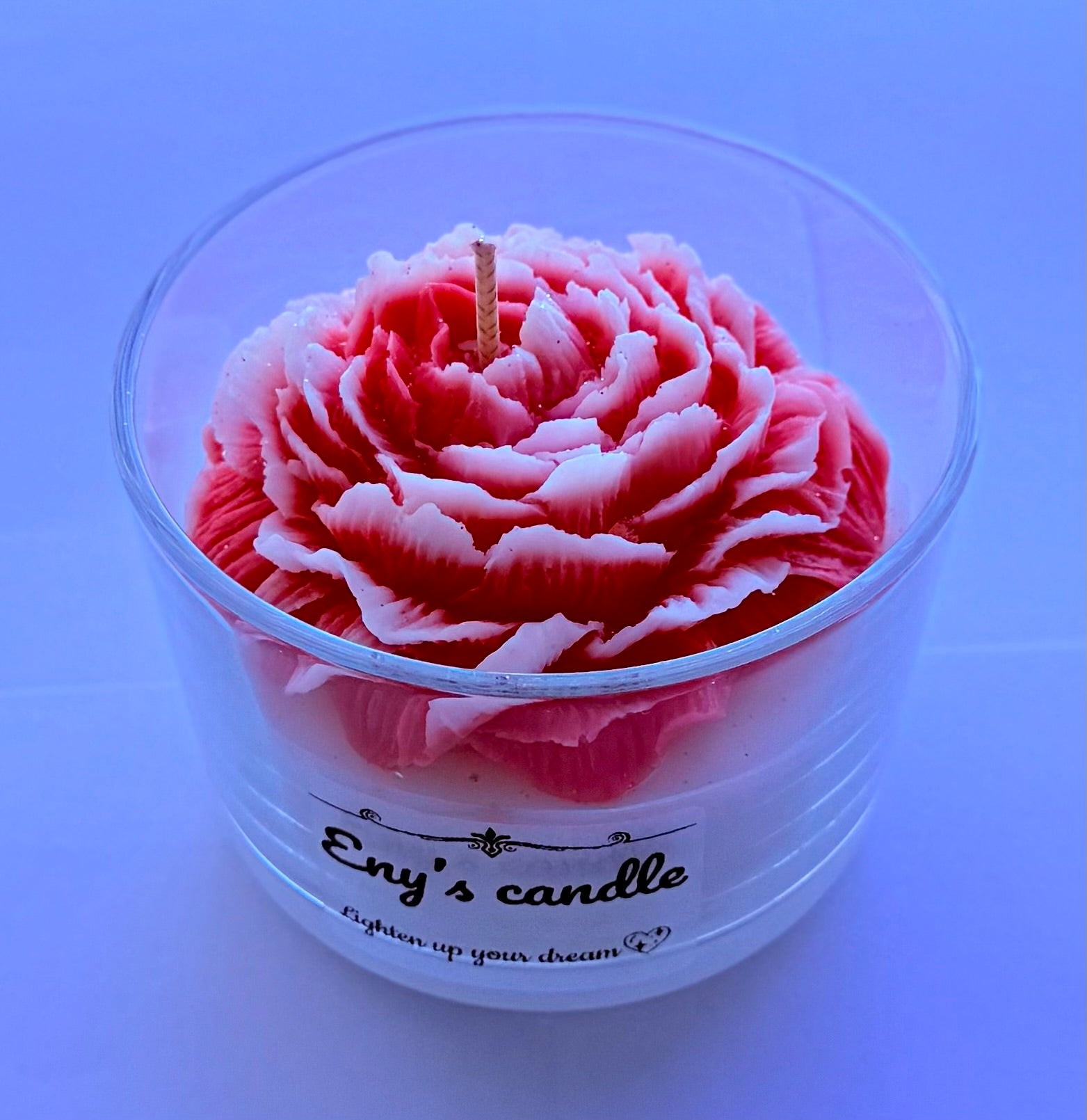 Handmade peony carved candle in red and white flower design inside a clear cup labeled ENY Candle House.
